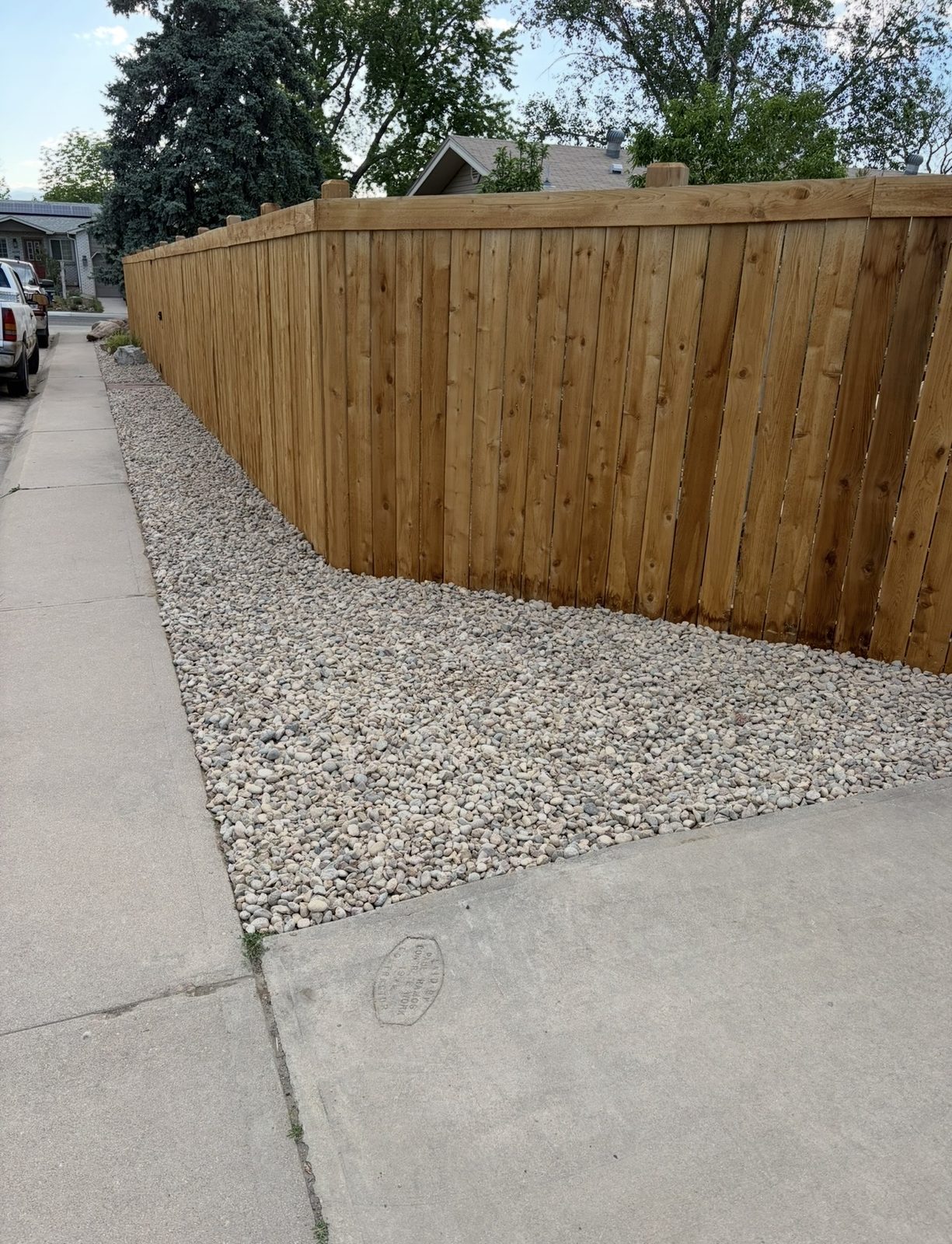 Corner of a cedar fence meeting a wide river rock bed