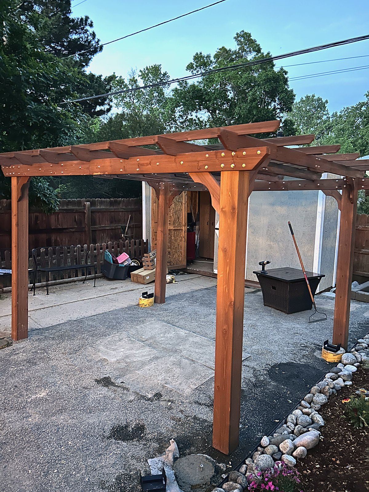 Cedar pergola standing over the patio at dusk, ground still being worked