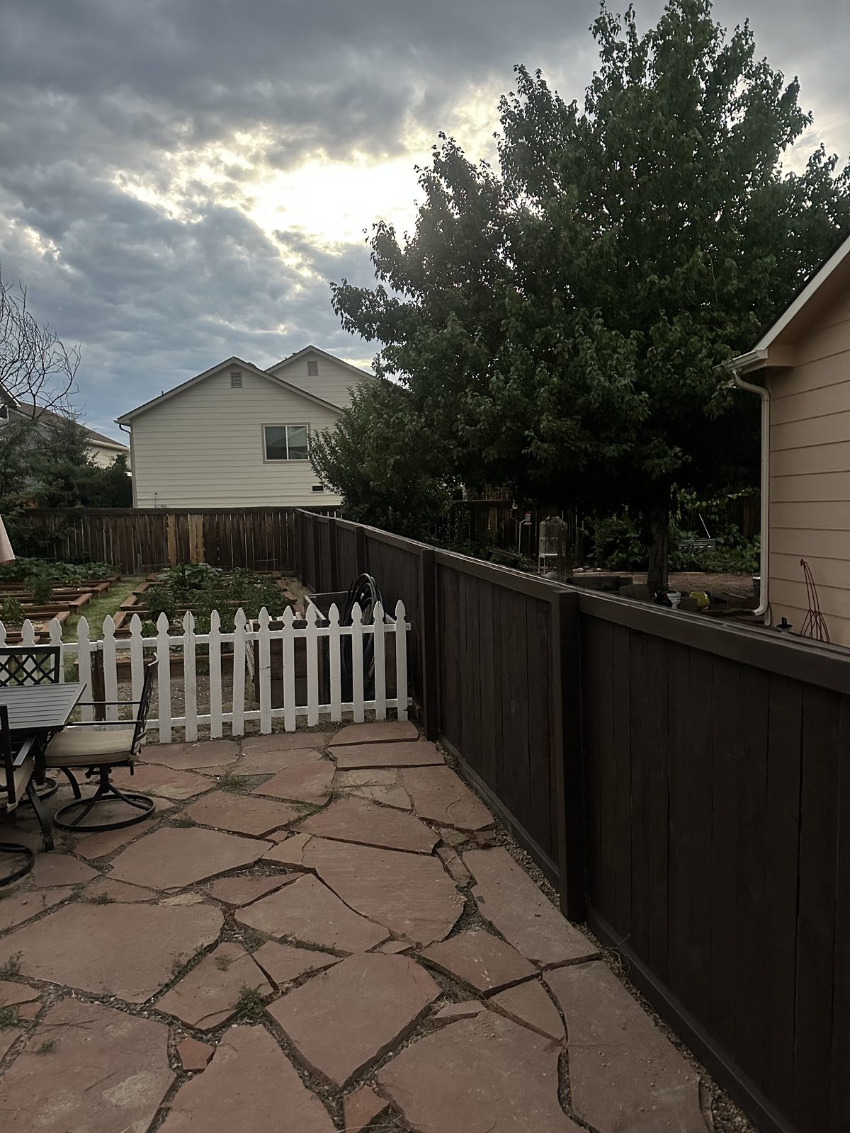 Flagstone patio beside a stained privacy fence