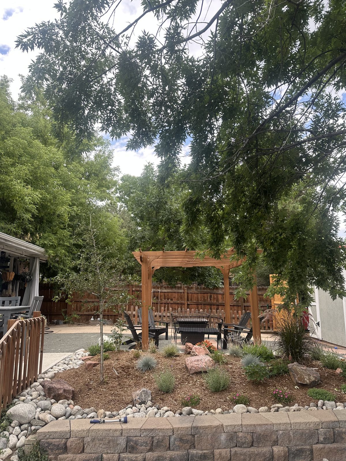 Cedar pergola over a patio with xeriscape beds and boulder work