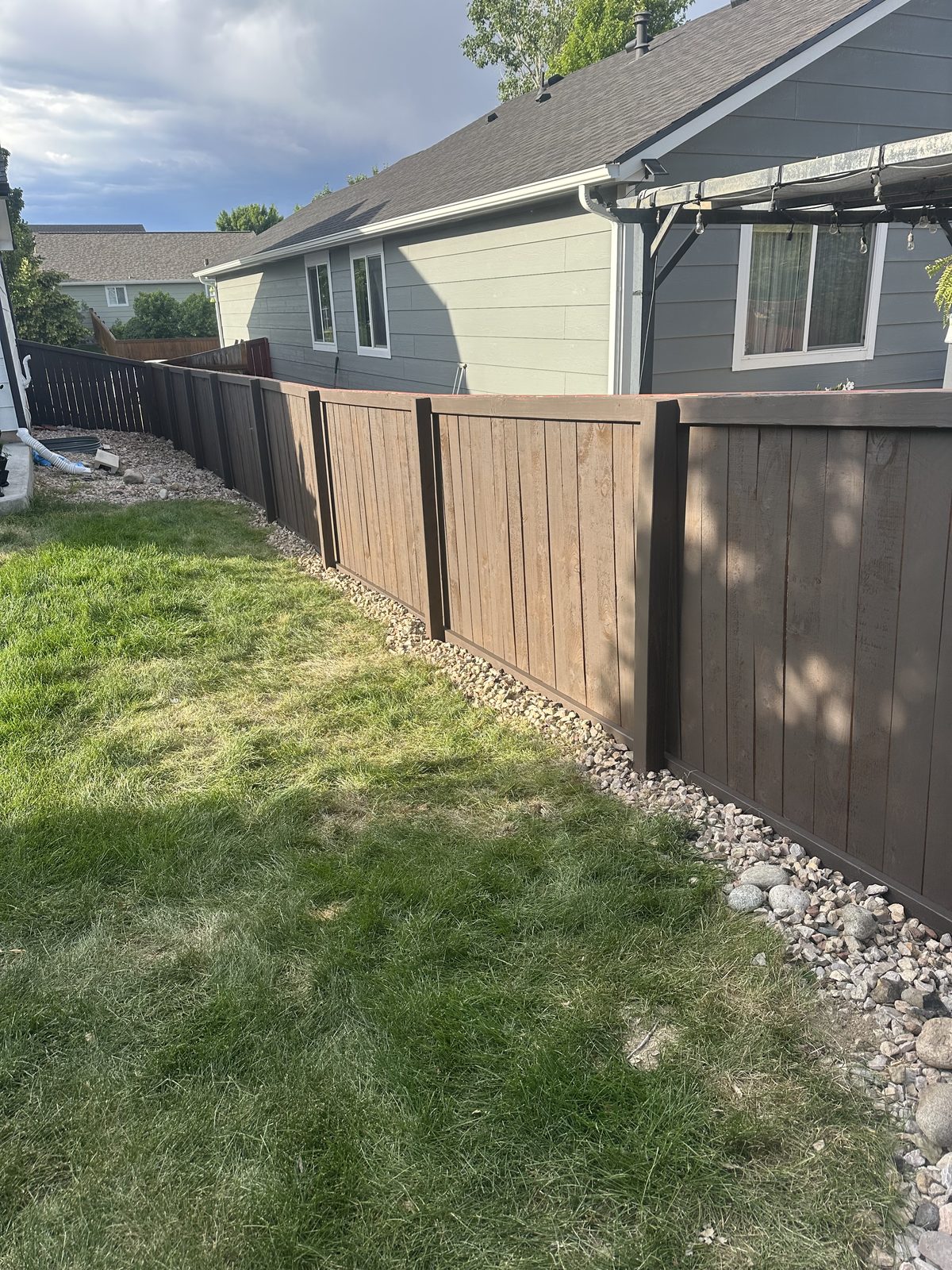 Stained privacy fence with a river rock drainage border